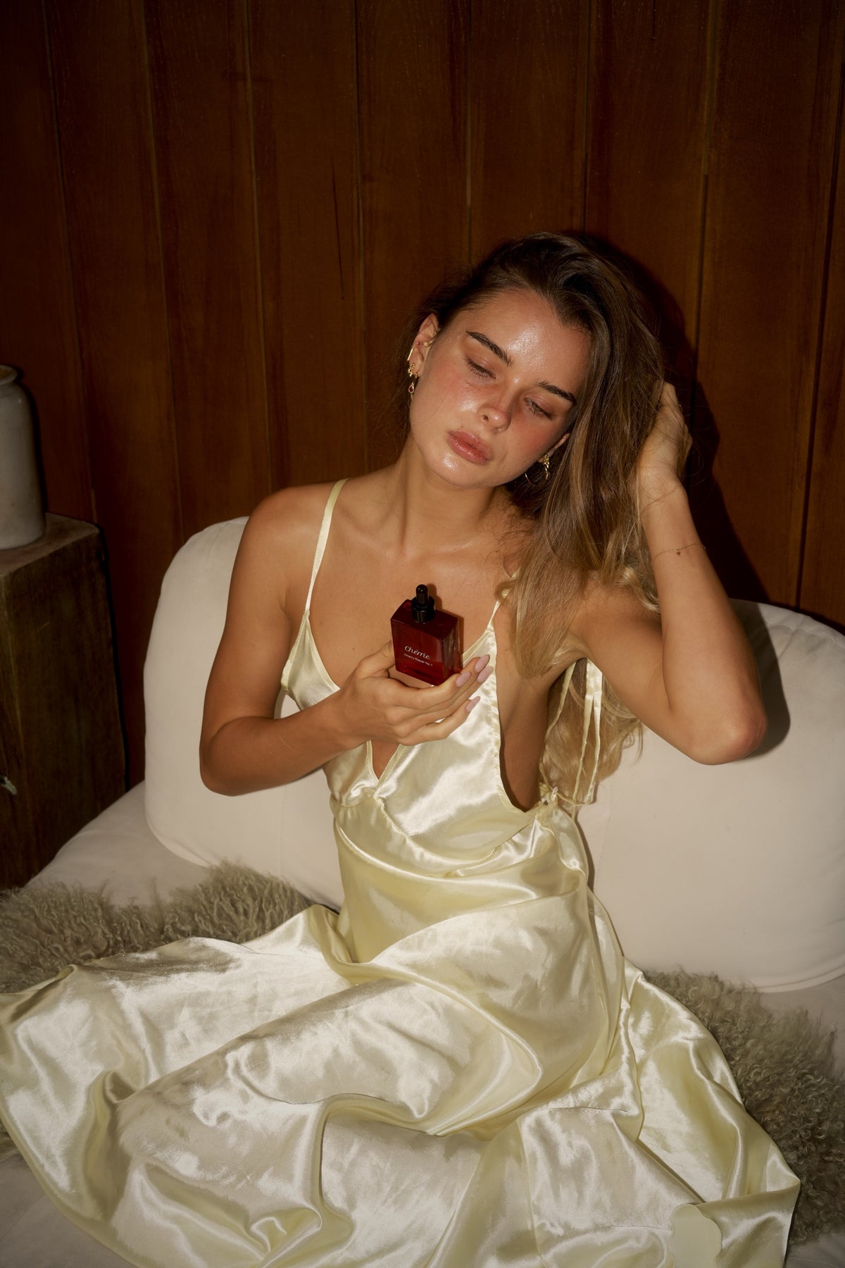 Woman in a cream satin slip holding Chèrrie Repair No.1 hair oil